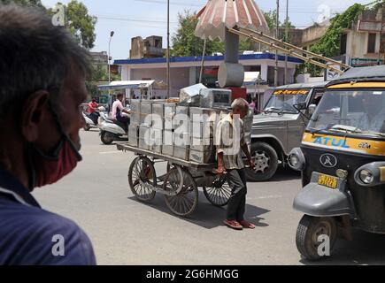 Beawar, Indien. Juli 2021. Der Arbeiter trägt an einem heißen Sommertag in Beawar Ölkisten auf seinem Wagen auf einem Markt. (Foto: Sumit Saleswat/Pacific Press) Quelle: Pacific Press Media Production Corp./Alamy Live News Stockfoto