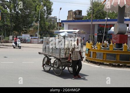 Beawar, Indien. Juli 2021. Der Arbeiter trägt an einem heißen Sommertag in Beawar Ölkisten auf seinem Wagen auf einem Markt. (Foto: Sumit Saleswat/Pacific Press) Quelle: Pacific Press Media Production Corp./Alamy Live News Stockfoto