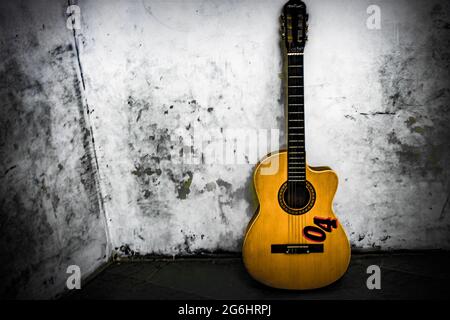 Gitarre an einer weißen Wand gelehnt Stockfoto