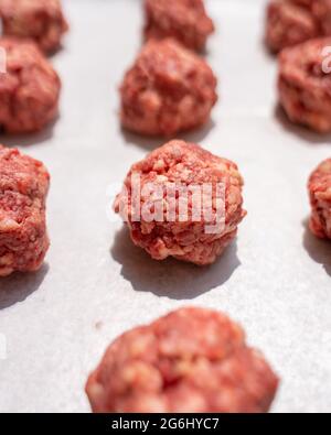 Reihen roher Fleischbällchen, die mit Hackfleisch auf Wachspapier zubereitet werden Stockfoto