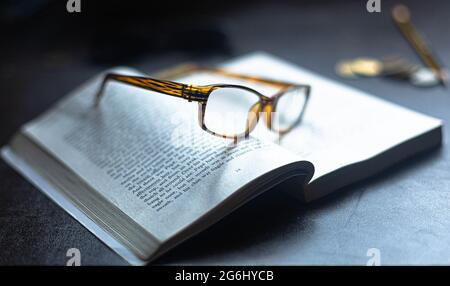 Eine Lesebrille, die auf einem offenen Buch ruht. Stockfoto