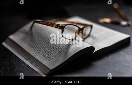 Eine Lesebrille, die auf einem offenen Buch ruht. Stockfoto