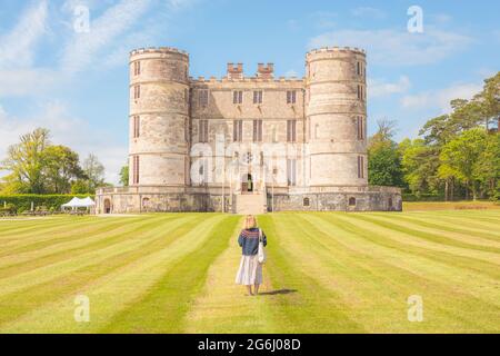 East Lulworth, Großbritannien - 25 2021. Juni: Eine junge blonde Frau, die im historischen Jagdschloss Lulworth Castle aus dem 17. Jahrhundert, Dorset, Großbritannien, Sightseeing macht Stockfoto