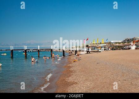 Antalya, Türkei-29. Juni 2021: Menschen, die im Sommer an der Küste spazieren, unter Sonnenschirmen schwimmen und sonnenbaden am Strand in Antalya. Stockfoto