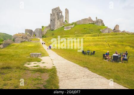 Corfe Castle, Großbritannien - 24 2021. Juni: Touristen besuchen an einem Sommertag die mittelalterlichen Burgruinen von Corfe Castle, Dorset, England. Stockfoto