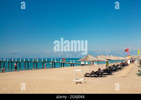 Antalya, Türkei-29. Juni 2021: Menschen, die im Sommer in Antalya auf dem Dock und an der Küste spazieren, schwimmen und sonnenbaden am Strand. Stockfoto