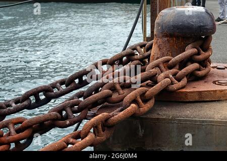Stud Link Art rostigen Schiff Ankerkette und eine Spitze Festmachen auf einem Fährhafen gebissen. Stockfoto