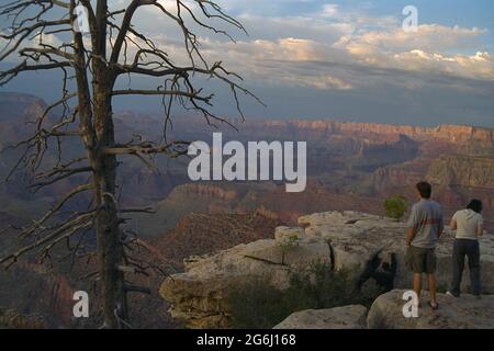 Menschen, die auf Felsen stehen und den Sonnenuntergang am Grand Canyon genießen Stockfoto