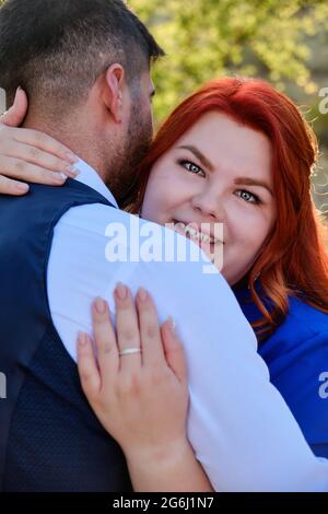 Frau umarmt ihren geliebten Mann und schaut auf eine Kamera Stockfoto