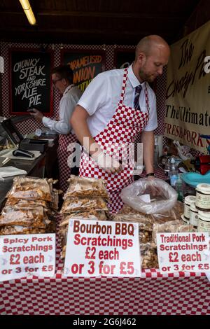 London, Großbritannien. 6. Juli 2021. Ein Arbeiter säcke traditionelle Schweinekratzer, um Besucher zu verführen, während das neu terminierte RHS Hampton Court Palace Garden Festival für die Öffentlichkeit geöffnet wird. Die größte Blumenschau der Welt wurde 2020 aufgrund der anhaltenden Coronavirus-Pandemie abgesagt und umfasst Gärten von inspirierenden Designern, Promi-Talks, Demonstrationen und Workshops. Besucher der Show müssen die Covid-19-Protokolle beachten. Kredit: Stephen Chung / Alamy Live Nachrichten Stockfoto