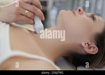 Arzt, der Ultraschall der Schilddrüse an junge Frau in der Klinik Stockfoto