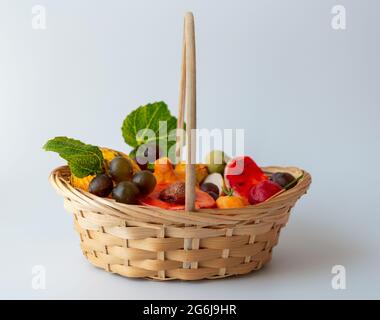 Handgemachte bunte Seifen in einem hölzernen Korbkorb auf weißem Backgorund.Seifen in Form von Früchten. Ausgefallene Früchte in einem kleinen Korbkorb. Stockfoto