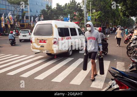 Jakarta, Indonesien. Juli 2021. Ein junger Mann trägt leere Sauerstofftanks zum Nachfüllen in Jakarta. Indonesien steht vor einer Sauerstoffkrise angesichts einer Zunahme der Covid-19-Fälle. Am 4. Juli kündigte die indonesische Regierung 2,284,084 bestätigte Fälle von COVID-19 in allen 34 Provinzen Indonesiens an, mit 295,228 aktiven Fällen und 60,582 Todesfällen. Kredit: SOPA Images Limited/Alamy Live Nachrichten Stockfoto