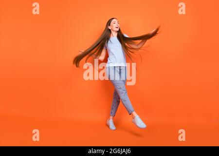 In voller Größe Foto von beeindruckt junge Dame Tanz tragen blaue T-Shirt Jeans isoliert auf orangefarbenem Hintergrund Stockfoto