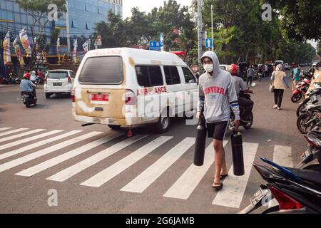 Jakarta, Indonesien. Juli 2021. Ein junger Mann trägt leere Sauerstofftanks zum Nachfüllen in Jakarta. Indonesien steht vor einer Sauerstoffkrise angesichts einer Zunahme der Covid-19-Fälle. Am 4. Juli kündigte die indonesische Regierung 2,284,084 bestätigte Fälle von COVID-19 in allen 34 Provinzen Indonesiens an, mit 295,228 aktiven Fällen und 60,582 Todesfällen. (Foto von Wisnu Agung Prasetyo/SOPA Images/Sipa USA) Quelle: SIPA USA/Alamy Live News Stockfoto