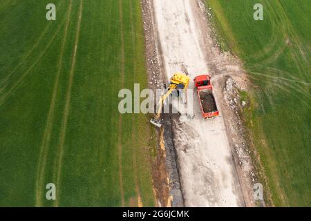 Bagger graben Boden in der Nähe des Feldes und Verladung auf den LKW Stockfoto