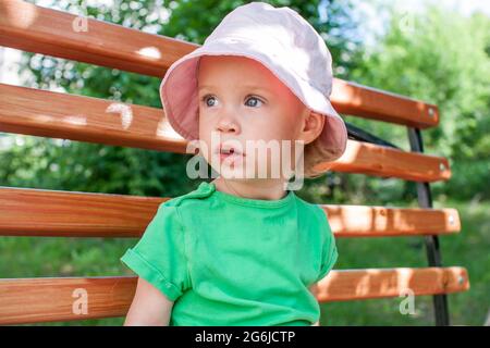 Kleines Mädchen in einem grünen T-Shirt und einem rosa panama spaziert im Sommer im Park Stockfoto