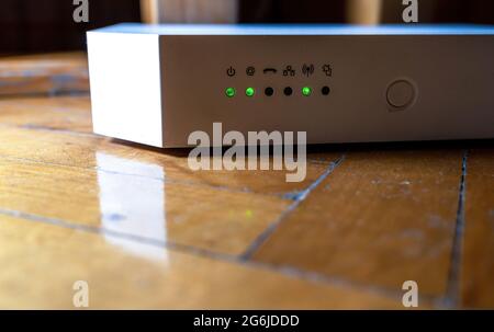 Advance weißer WiFi-Router, asymmetrisches digitales Teilnehmerleitungsmodem mit blinkenden LEDs, die die Aktivierung von Internetdaten anzeigen. Stockfoto
