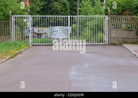 Metalltor am Ende der Asphaltstraße. Stockfoto