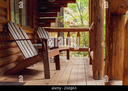 Veranda der rustikalen Blockhütte mit hölzernen Adirondack-Stühlen Stockfoto