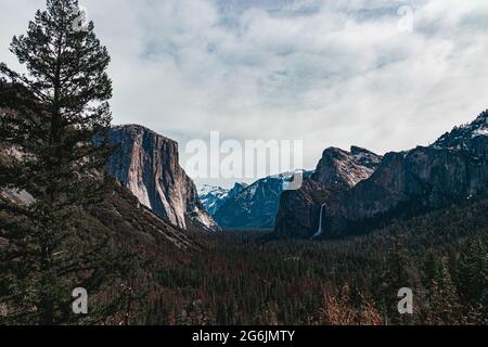 Klassischer Tunnel Blick auf das malerische Yosemite Valley mit dem berühmten El Capitan und Half Dome Klettergipfeln an einem bewölkten Tag, Kalifornien Stockfoto