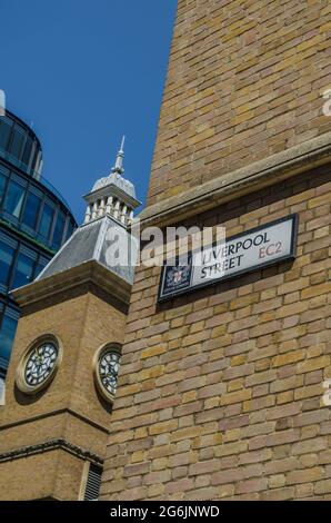 Ein Straßenschild vor der Londoner Liverpool Street Station mit einem Uhrenturm im Hintergrund. Es gibt einen blauen Himmel an einem heißen Sommertag in der Stadt. Stockfoto