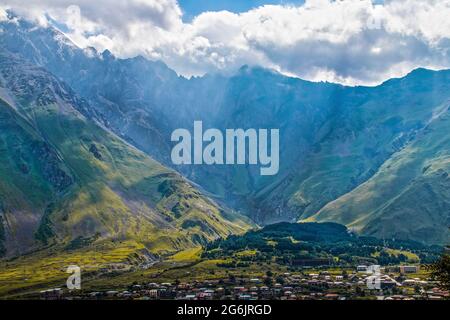 Blick über die Dächer des Dorfes Stepantminda in Georgien - acht Meilen von Russland - über das Tal zu den Kasbek Bergen mit Stockfoto