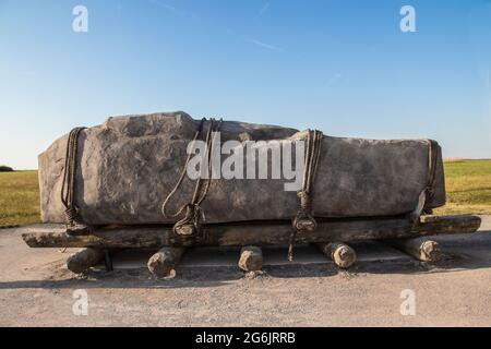 Stehender Stein horizontal auf Schlitten mit Rollen, die mit Seilen wie die Steine bei Stonehenge gebunden sind, könnte verschoben worden sein Stockfoto