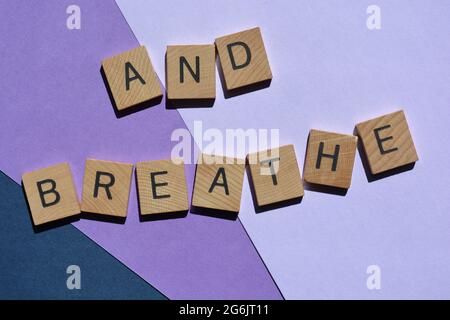 Und atmen, Wörter in 3d-Holzalphabetatbuchstaben isoliert auf violettem Hintergrund Stockfoto