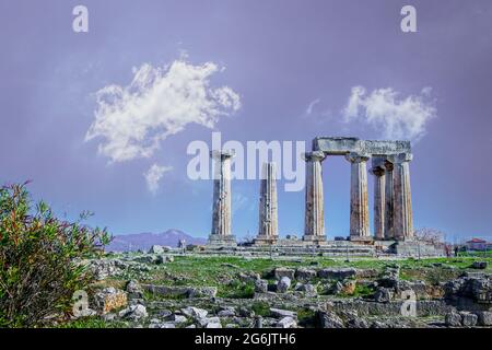 Die Ruinen des Tempels von Apollo, der hoch auf einem Hügel in Korinth Griechenland über Trümmern mit purpurnen Bergen in der Ferne und wiisy Wolken über ihm steht Stockfoto