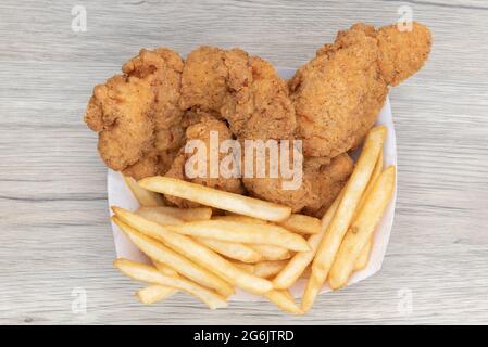 Ansicht von oben über frittierte Mahlzeit mit Streifen panierten Hähnchens und einer Beilage von pommes frites. Stockfoto