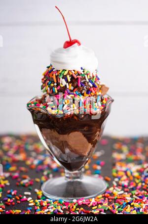 Ein Schokoladen-Eisbecher mit Schokoladensirup und Regenbogenstreuseln Stockfoto