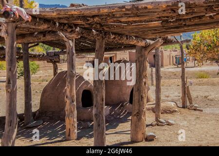 Zwei Hornos-traditionelle Erdöfen - unter einem Trockengestell mit einer Kinderpuppe an der Ecke - Häuser der Ute Pueblo in Taos New Mexico in t Stockfoto