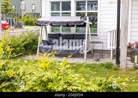 Blick auf niedliche Schaukelstühle auf dem Hinterhof des privaten Hauses. Schweden. Stockfoto