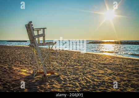 Verlassene hölzerne Rettungsschwimmersessel am Strand mit Sonnenfleck am Himmel - Great Lakes USA. Stockfoto