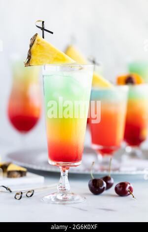 Gläser mit frostigen bunten Mocktails, umgeben von Früchten zum Garnieren. Stockfoto
