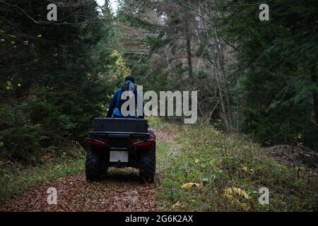 Männlicher Helfer in Schutzuniform auf einem Quad-Bike Beobachten Sie die Wälder, um eine vermisste Person zu suchen und zu retten Stockfoto