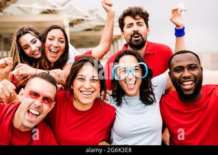 Multirassische Zuschauergruppe in Teamfarben beim Fußballschauen im Stadion Stockfoto