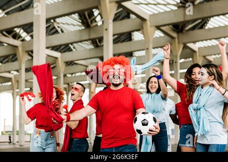 Fröhliche, multirassische Fans, die sich vor dem Stadion gemeinsam amüsieren Stockfoto