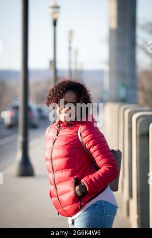 Eine fröhliche, modische Frau im Freien entlang der Straßen der Stadt. Stockfoto