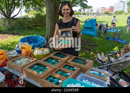 Während eines Protestes gegen die Pläne des Gouverneurs Andrew Cuomo für ein COVID-19-Denkmal in New York City überreicht eine Frau grüne Cupcakes.zweihundert Demonstranten versammelten sich im Rockefeller Park in Lower Manhattan, um den Druck auf Gouverneur Andrew Cuomo nur wenige Tage nach dem mächtigen und skandalumwitterten Staat aufrecht zu erhalten Anführer nixed seine Pläne, einen Teil der Grünfläche für das „Kreis der Helden“-Denkmal, das Coronavirus-Denkmal, zu pflastern. Der Protest der Battery Park City ereignete sich, als der Gemeinderaum 1, der das Gebiet vertritt, ein Mittwochstreffen anberaumt, um das Denkmal zu diskutieren. Stockfoto