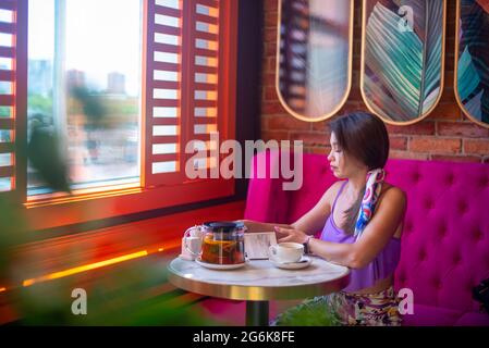 Eine asiatische Frau sitzt an einem Tisch in einem Café Stockfoto