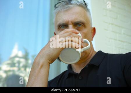 Ein Mann mit ernsthafteren Gesichtes, der im Freien Tee oder Kaffee trinkt Stockfoto