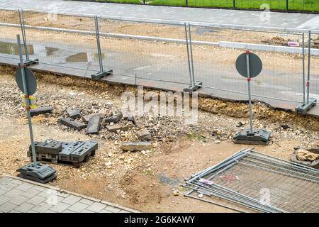 Die Straße wird erneuert, die Bauarbeiten laufen. Hindernisse behindern die Fußgänger und Autofahrer. Der Bürgersteig ist aufgerissen, Steine und Schmutz Stockfoto