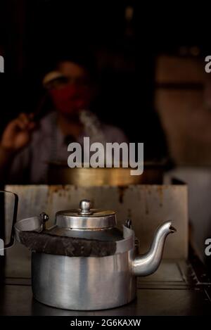 Kessel von heißen Chai mit verschwommenem Bild des Verkäufers, der das gleiche macht Stockfoto