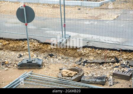 Die Straße wird erneuert, die Bauarbeiten laufen. Hindernisse behindern die Fußgänger und Autofahrer. Der Bürgersteig ist aufgerissen, Steine und Schmutz Stockfoto