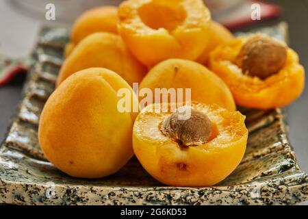 Frische Aprikosen ganz und in die Hälfte mit den Samen geschnitten, fertig zum Essen Stockfoto