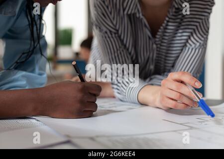 Nahaufnahme verschiedener Architektinnen, die am Schreibtisch an Blaupausen arbeiten. Professionelles Ingenieur-Team entwerfen Baulayout für Gebäude Modell Maquette Projekt-Design Stockfoto