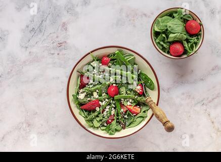 Frische Erdbeeren, grüner Spargel, Feta-Käse, Babyspinat und Rucola-Salat in einer Schüssel serviert. Saisonales Mittagessen, sauberes Essen, vegetarisches Essen. Top V Stockfoto