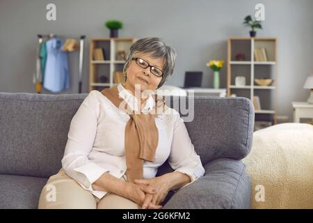 Selbstbewusste, stilvolle ältere, ältere Frau mittleren Alters sitzt im Heimbüro auf dem Sofa Stockfoto